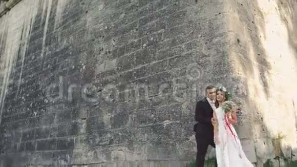 城堡附近的一对漂亮的新婚夫妇亲吻和微笑4K视频的预览图