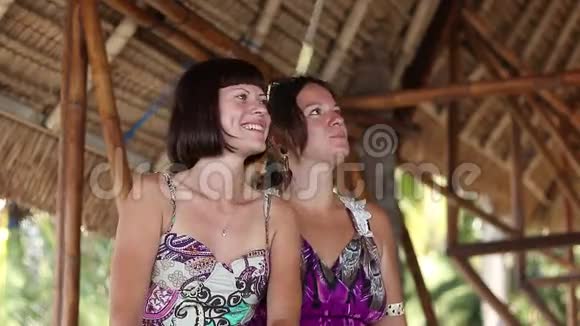 两位美丽迷人的年轻女性坐在印度尼西亚巴厘岛热带海滩附近的特写肖像亚洲视频的预览图