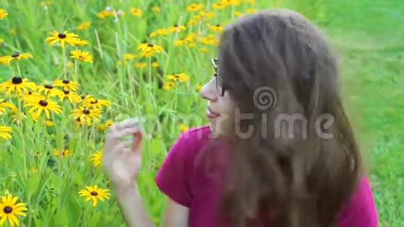 在花旁摆姿势的年轻美丽时尚女性的户外画像视频的预览图