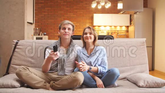 年轻夫妇在客厅沙发上看电视视频的预览图