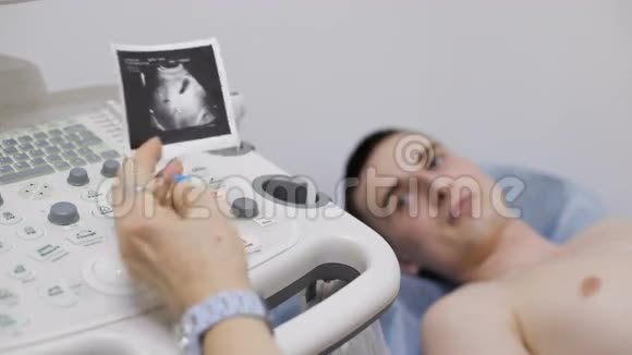 关闭男性放射科医生操作超声波机器并在键盘上打印超声波图视频的预览图