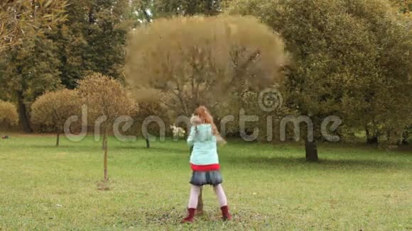 小女孩在秋天公园里摇一棵树视频的预览图