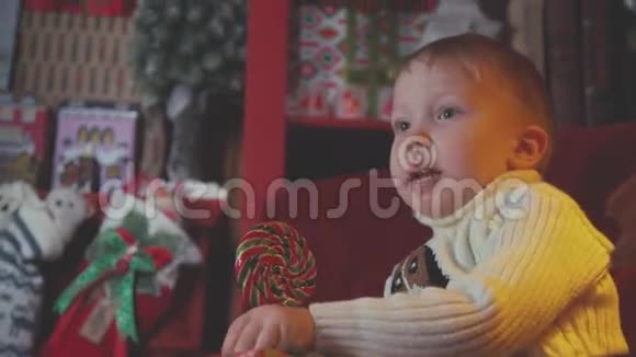 胖乎乎的小男孩吃着五颜六色的圆形圣诞糖果视频的预览图