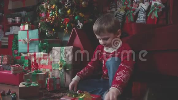 穿圣诞毛衣的男孩打开礼物圣诞节早晨视频的预览图