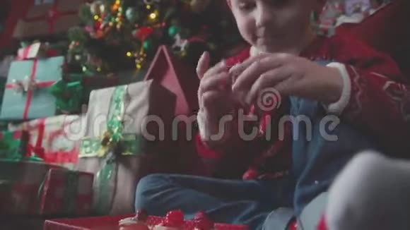 男孩坐在圣诞树附近的地板上检查礼物视频的预览图