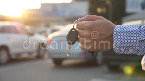 年轻的商人在室外停车场散步手里拿着车钥匙商人带着车钥匙的手臂盖盖视频的预览图