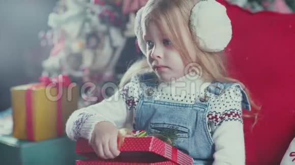 穿毛衣的可爱女孩打开一个盒子里面有礼物然后拿出一颗糖果视频的预览图