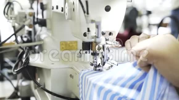 在一家工厂里一个女人正在缝制一件蓝白衬衫视频的预览图