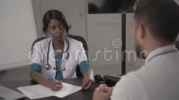 白衣医生在办公室检查男性病人血压非裔美国黑人护士在医院与视频的预览图