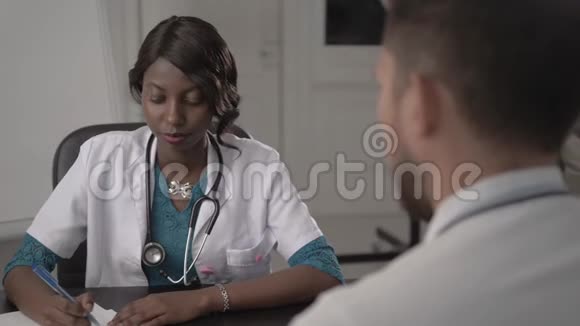 白衣医生在办公室检查男性病人血压非裔美国黑人护士在医院视频的预览图