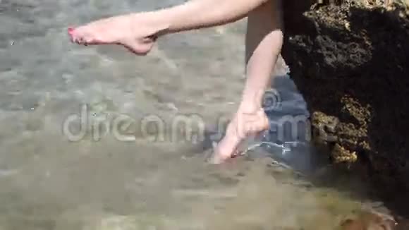 女孩在海中飞脚坐在岩石上视频的预览图