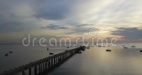在美丽的日落中可以看到环绕大海的码头大桥的空中景色展示水面上的船只无人机拍摄录像视频的预览图