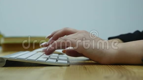 在桌子旁的现代办公室用电脑键盘上的女人手打字的特写镜头视频的预览图