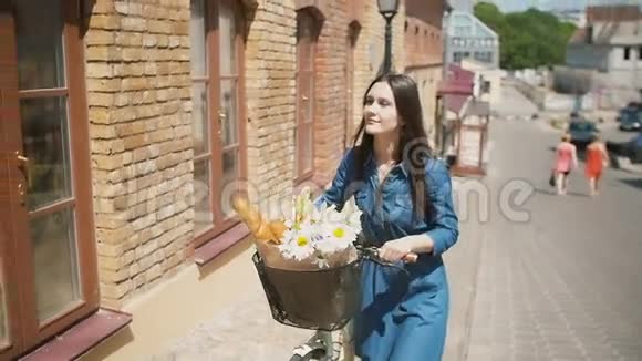 女孩骑着自行车上街花篮里放着鲜花夏日阳光明媚慢吞吞的斯泰迪卡姆镜头视频的预览图