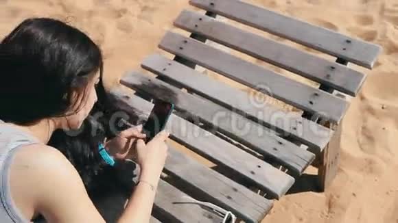 躺在沙滩躺椅上的女孩移动智能手机触屏视频的预览图