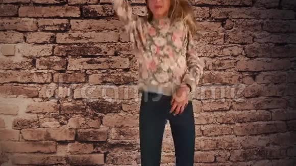 美丽的女孩站在墙边跳着跳舞玩着头发摇着头视频的预览图