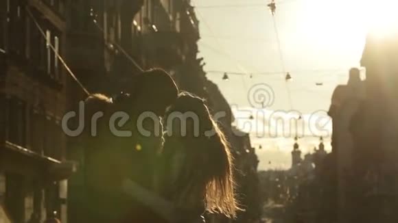 迷人的年轻情侣在夕阳下温柔地接吻冬季早晨的欧洲城市街道背景视频的预览图