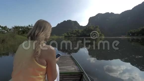 越南TrangAn船游期间带手机拍照的女旅行者视频的预览图
