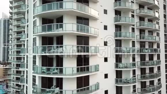 迈阿密阳光明媚的艾尔斯海滩附近阳台上有日光浴床的舒适酒店的航拍照片视频的预览图