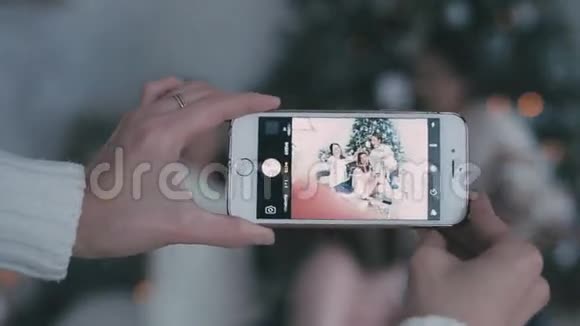 在圣诞树的背景下给智能手机女孩拍照视频的预览图
