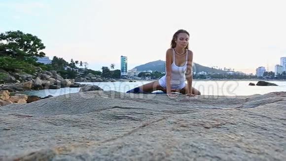 金发女郎躺在石头上从海滩上的瑜伽软管莲花视频的预览图