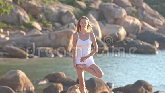 年轻的金发女郎在沙滩上展示瑜伽筒视频的预览图