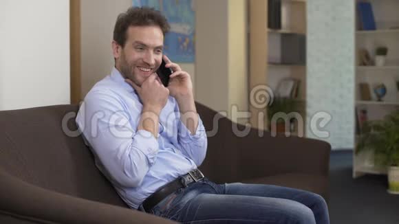 男性自由职业者坐在沙发上用手机聊天交流视频的预览图