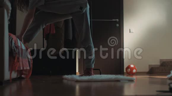 客厅里一个年轻灵活的女孩在地毯上滑倒不小心弄裂缝视频的预览图