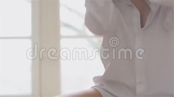 一个穿着白色衬衫的漂亮年轻女人坐在大厅的地板上视频的预览图