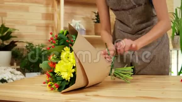 年轻的女设计师把花包在包装纸里快乐的女孩在花店工作视频的预览图