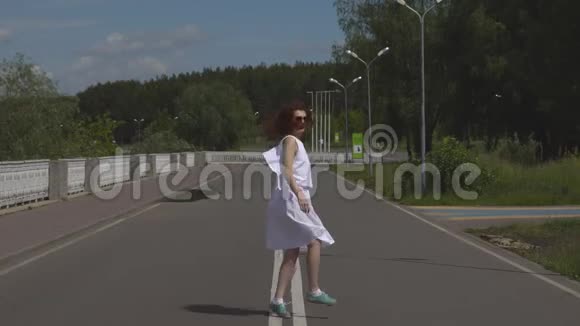 年轻漂亮的女孩戴着太阳镜和白色裙子走在户外视频的预览图