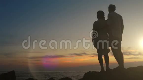 日落时分一对夫妇站在悬崖上俯瞰大海视频的预览图
