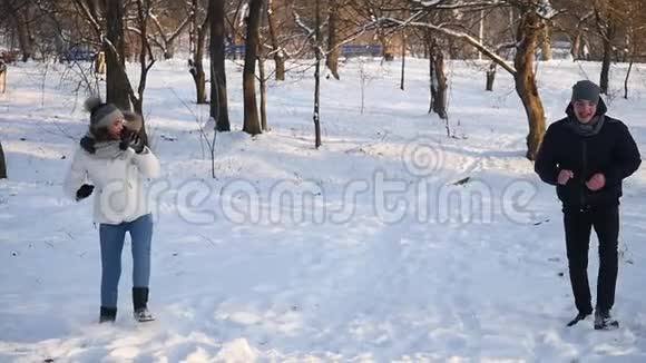 男人和女人的一对夫妇在一片白雪皑皑的冬林里互相扔雪球视频的预览图