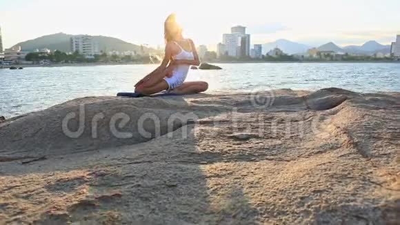 落基海滩腰部瑜伽脚的金发女郎视频的预览图