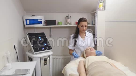 在化妆过程中女人躺在沙发上专业美容师正在水疗中心做面部按摩视频的预览图