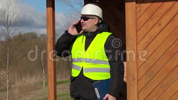 土木工程师在大楼的木质结构上用智能电话交谈视频的预览图