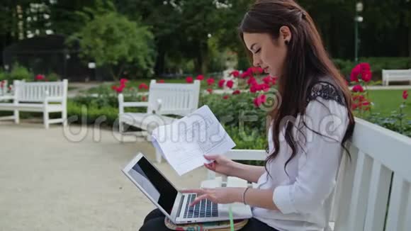女士坐在公园里用笔记本电脑数据输入视频的预览图