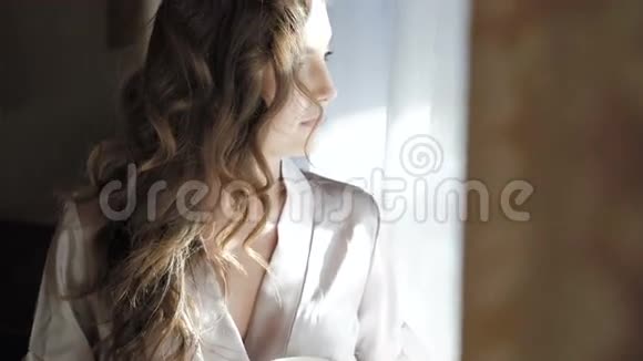 穿夜装的漂亮女孩在窗户附近喝了一杯咖啡视频的预览图