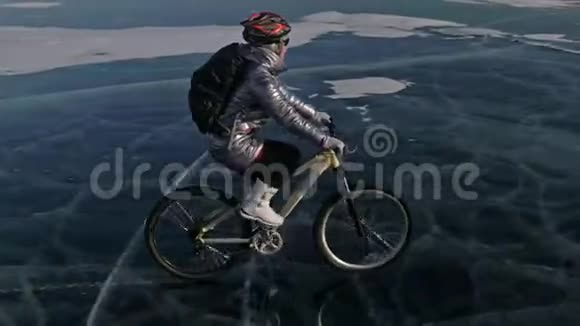 女人在冰上骑自行车女孩穿着银色羽绒服自行车背包和头盔射击视频的预览图