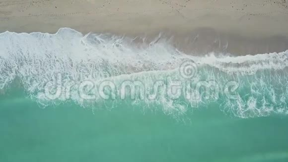 在迈阿密阳光明媚的艾尔斯海滩靠近白色沙滩海岸的图尔奎斯波浪状海水上空飞行视频的预览图