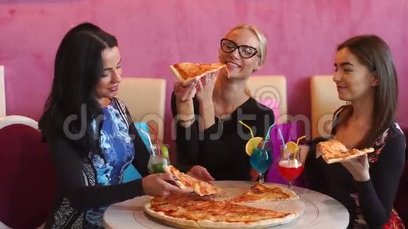 三个漂亮的美女坐在意大利餐馆里吃着比萨饼微笑着他们喜欢吃美食视频的预览图