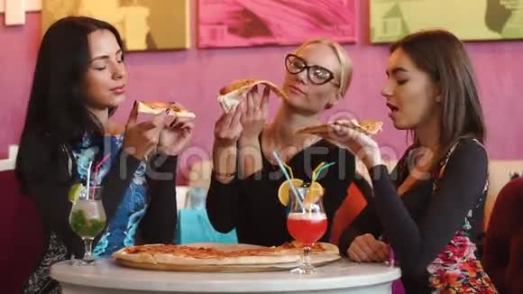 三位有魅力的女士在意大利餐厅吃披萨他们喜欢吃好的食物和喝鸡尾酒视频的预览图