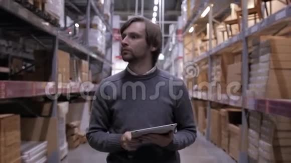 人使用平板电脑对货架与箱子在仓库现代股票中心的帅哥销售员视频的预览图