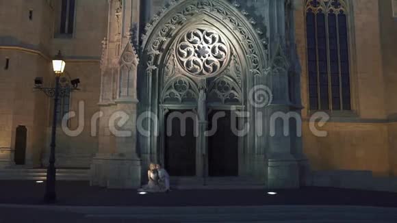 浪漫性感的新婚夫妇坐在古哥特教教堂门口视频的预览图