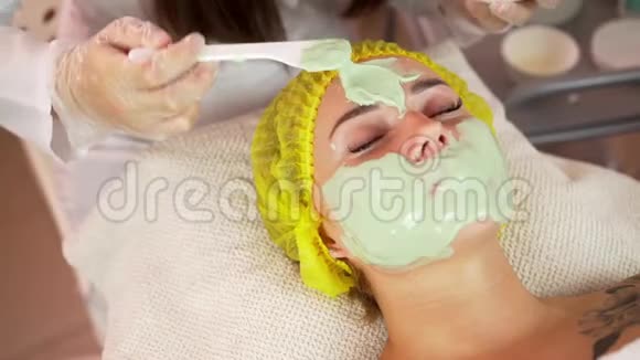 美丽的黑发女人在健康水疗中心接受面部护理视频的预览图