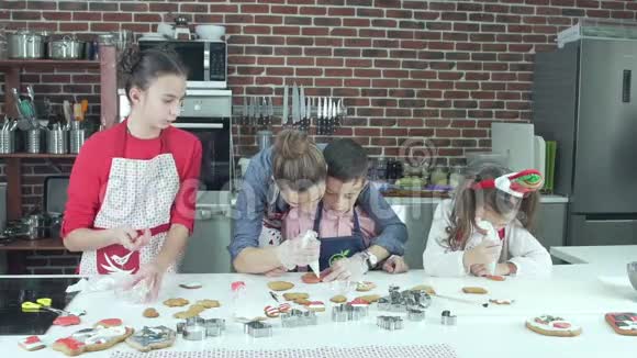 三个孩子和他们的母亲烤饼干并装饰它视频的预览图