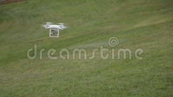 白色无人机四架飞机在草地背景下的蓝天上飞行视频的预览图