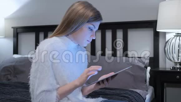 女人在卧室里使用平板电脑时对成功做出反应视频的预览图