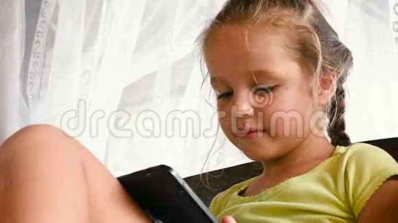 在床上学习的白人小女孩在卧室里玩平板游戏视频的预览图