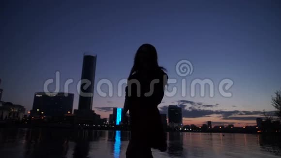 夜晚在河岸上女孩的剪影视频的预览图
